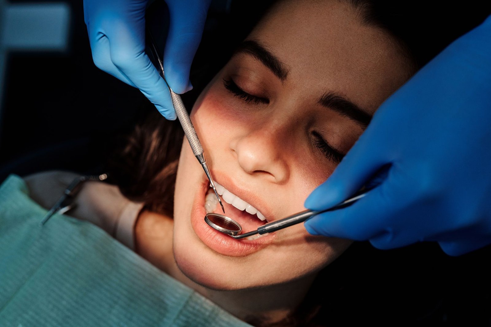 Dentist examining a patient's teeth with a mirror and probe during a dental exam